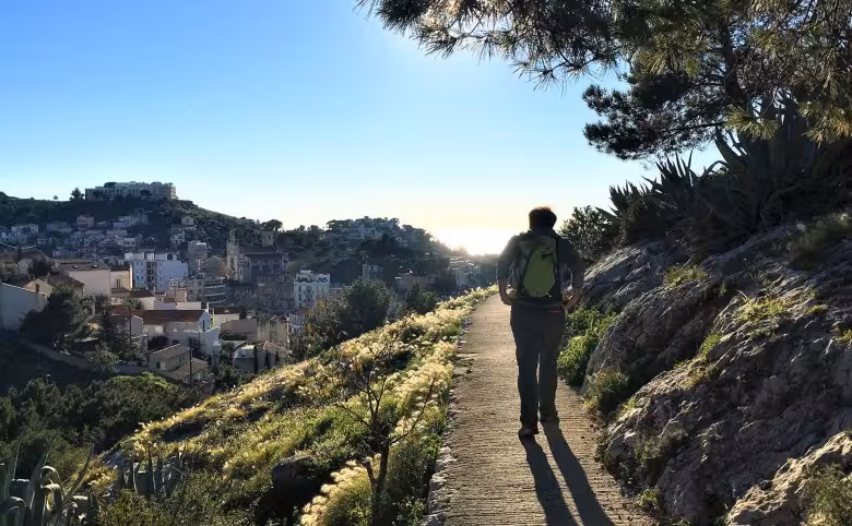 Hiker on Marseille hillside trail at sunrise, urban hike from Notre-Dame de la Garde to the sea