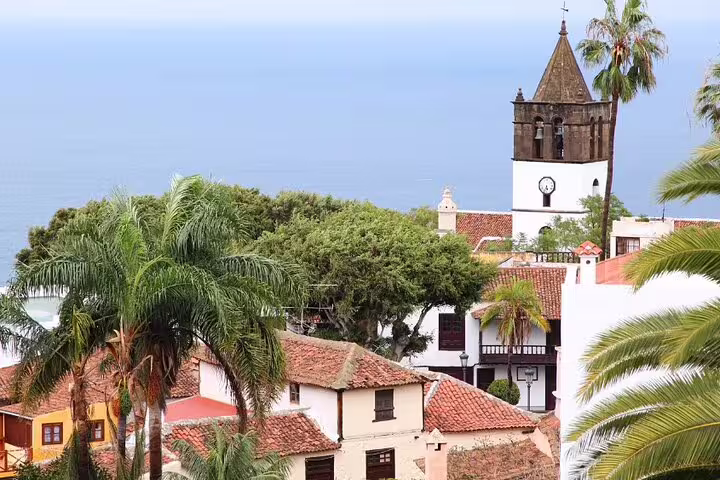 Scenic view of Masca village in Tenerife with traditional architecture surrounded by lush greenery and palm trees.