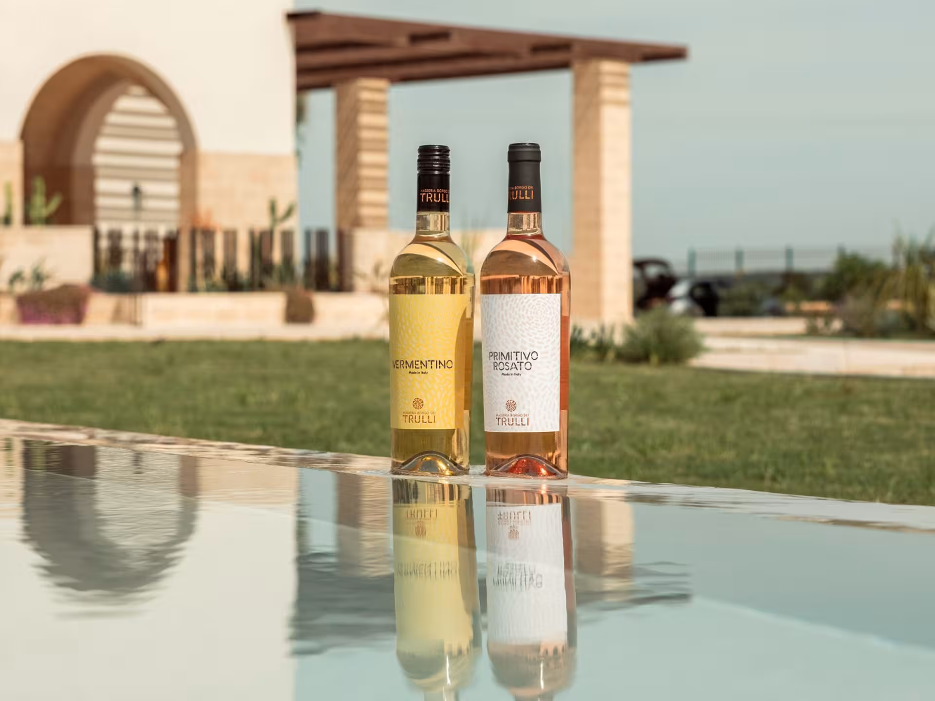 Two wine bottles reflecting on a table at a Masseria winery near Taranto, ideal for tasting tours and vineyard visits.