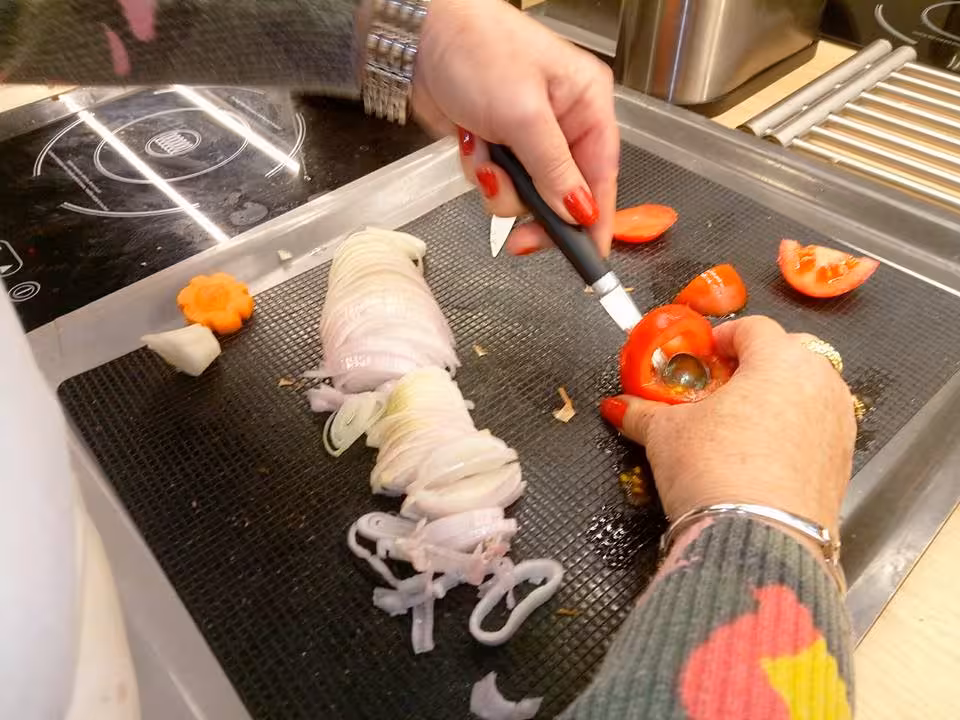 Hands slicing tomatoes and onions on a board during a Master Chef cooking workshop in the South of France