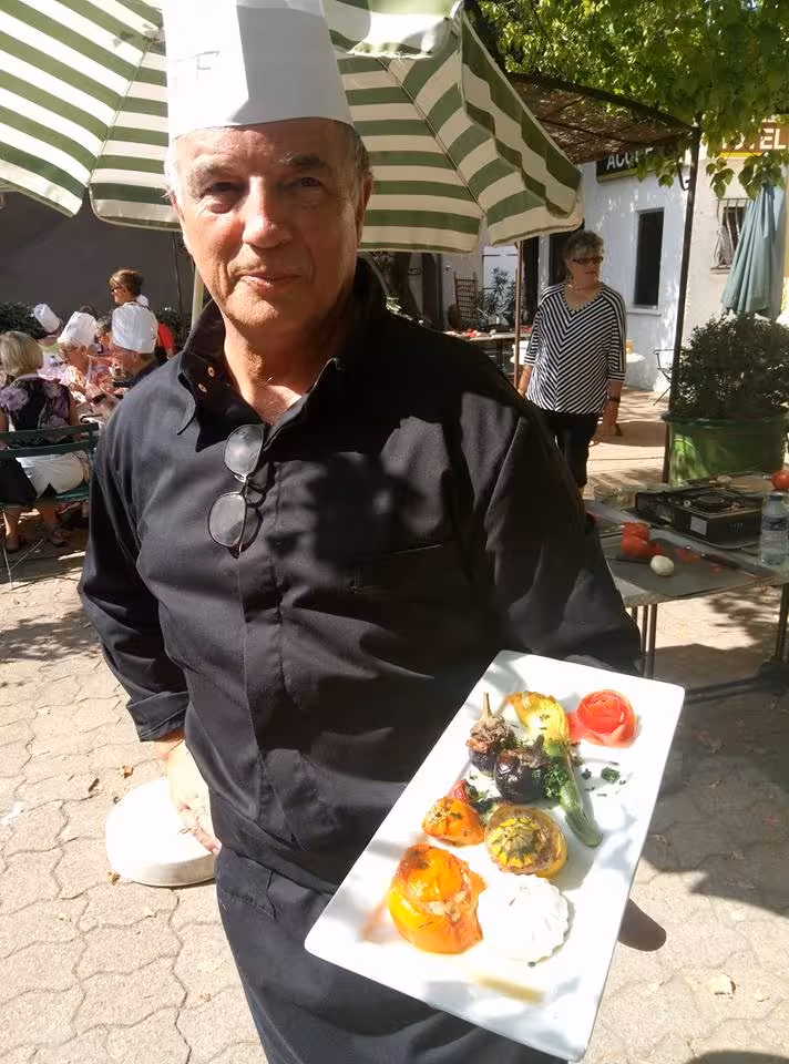 Master chef presenting colorful Provençal tasting plate at an outdoor cooking workshop in the South of France