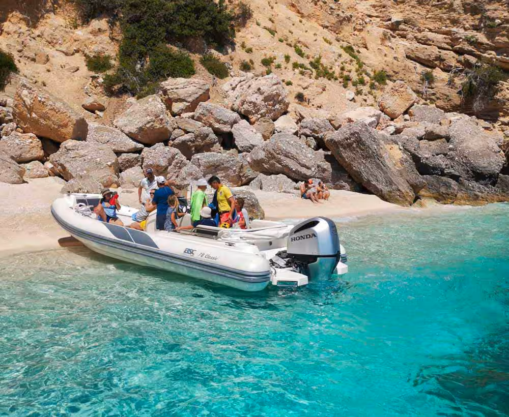 Tourists enjoy a Maxi dinghy tour with aperitif on a picturesque beach in the Gulf of Orosei, Sardinia.