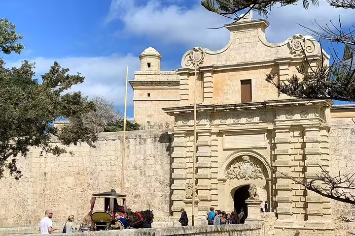 Visitors explore the historic entrance of Mdina, showcasing Malta's rich architectural heritage.