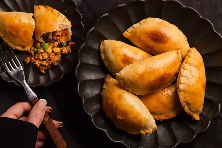 Plate of golden-brown empanadas filled with savory meat and vegetables in Medellín's Laureles street food tour.