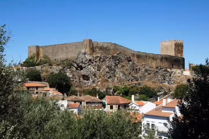 Majestic medieval castle overlooking a picturesque Portuguese village, ideal for a historical day tour.