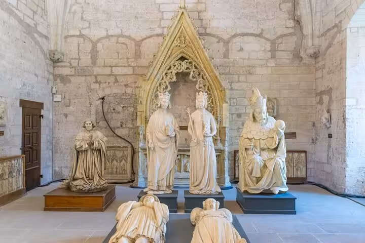 Intricate medieval sculptures in a historic stone room at the Papal Palace in Avignon, showcasing religious figures.