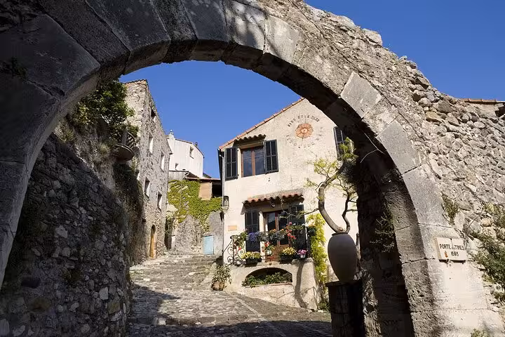 Charming medieval village entrance with cobblestone path and rustic stone archway on private tour.