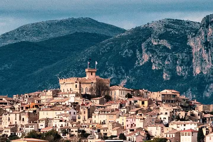 Scenic view of a medieval village with historic architecture nestled against lush mountainous terrain.