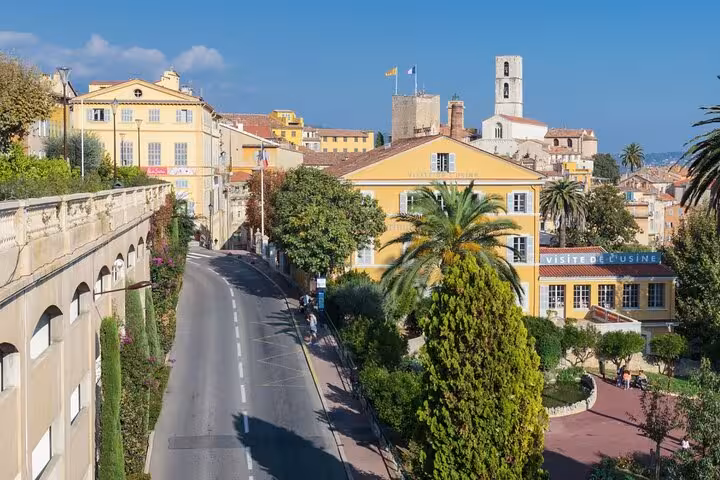 Scenic view of a medieval village street in Provence, lined with trees and showcasing traditional Provencal architecture.