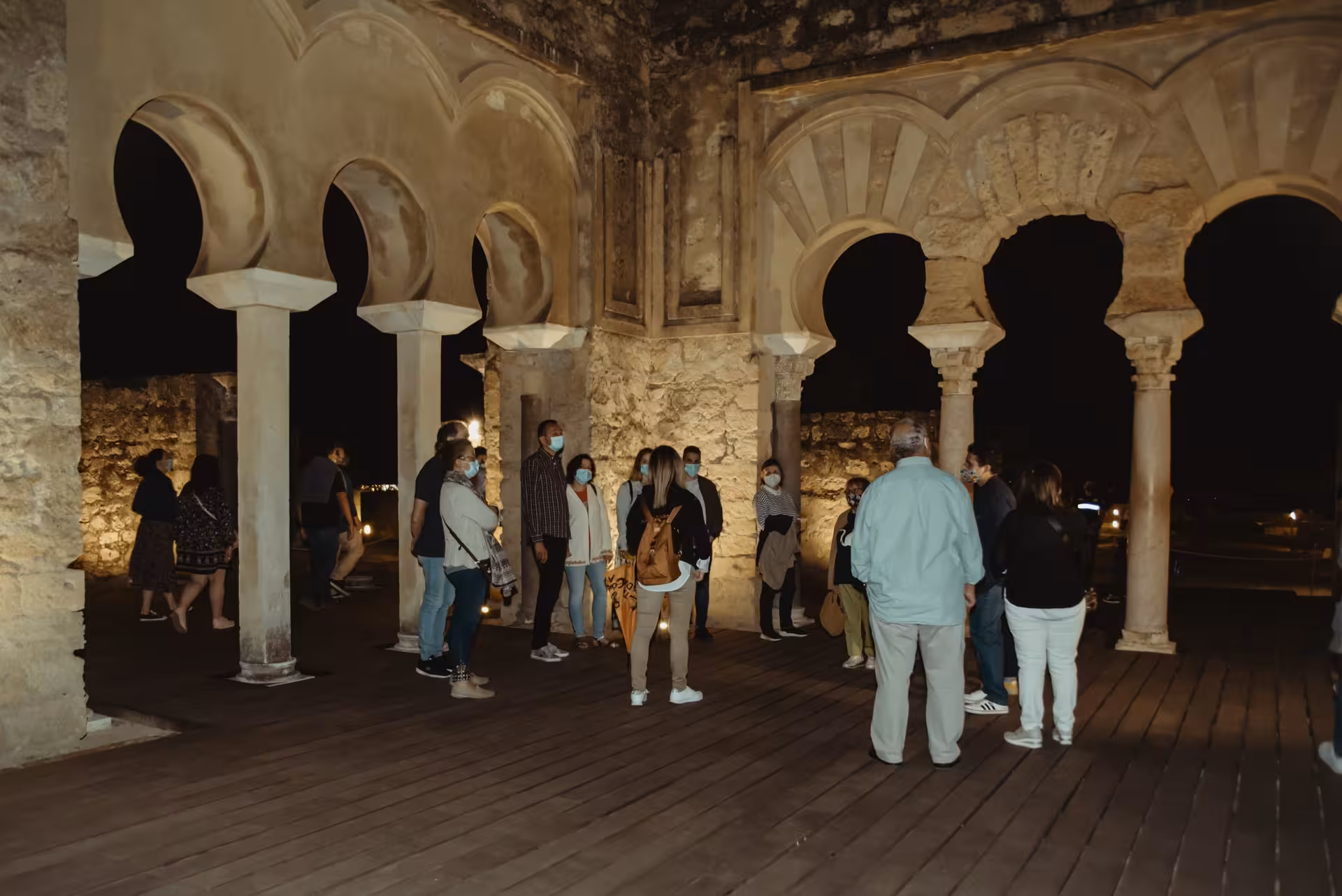 Visitors explore Medina Azahara's historic arches during an enchanting guided night tour under the moonlit sky.