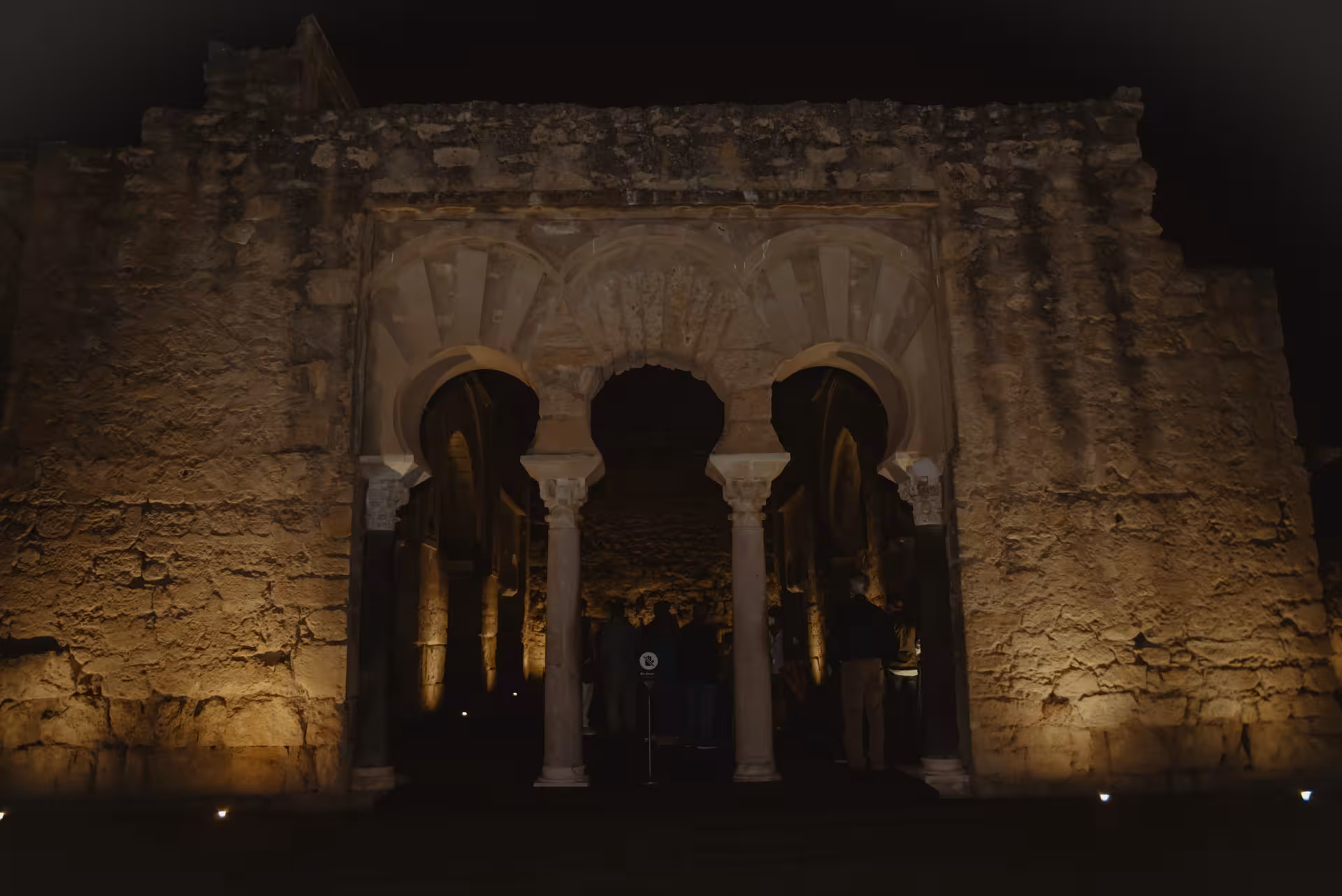 Illuminated arches of Medina Azahara at night, highlighting the ancient Moorish architecture on a guided tour.