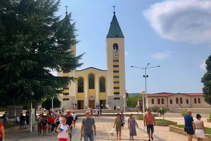 Pilgrims walking to St James Church in Medjugorje on a private tour, iconic twin bell towers