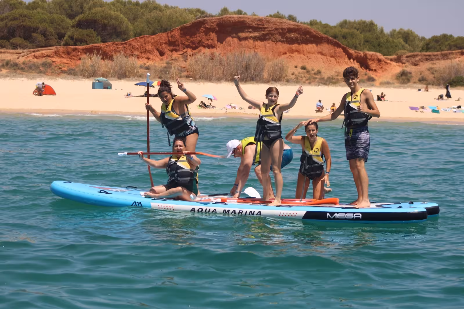 Smiling group stands and poses on a Mega Paddle board during a fun Algarve coast SUP rental experience