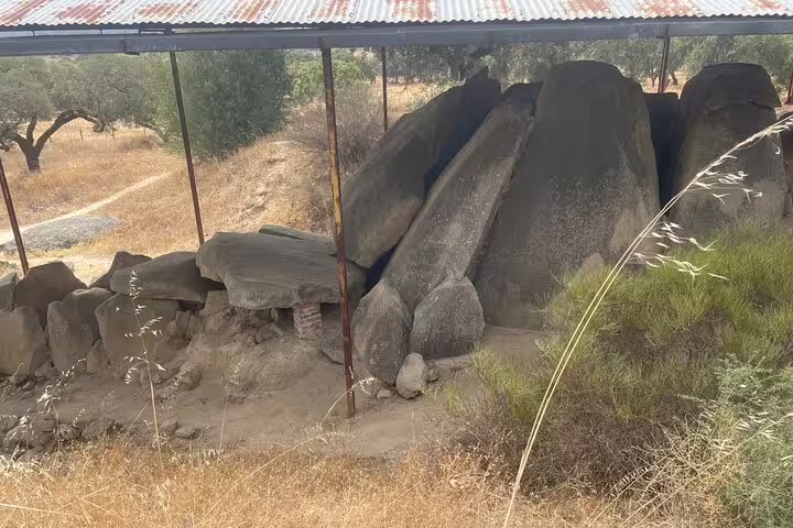 Protected megalithic dolmen structure under a canopy, showcasing ancient architecture near Évora.