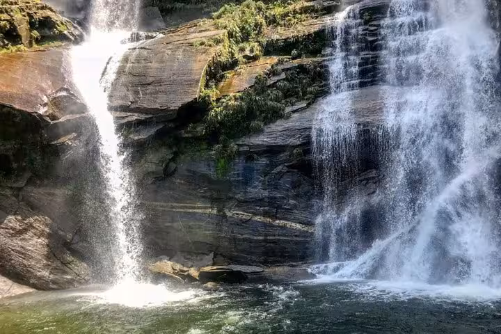 Picturesque Melancia Waterfall cascading over rocks surrounded by lush greenery in Paraty, Brazil.