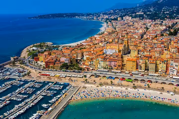 Aerial view of Menton's colorful coastline with vibrant buildings and bustling marina, perfect for a picturesque tour.