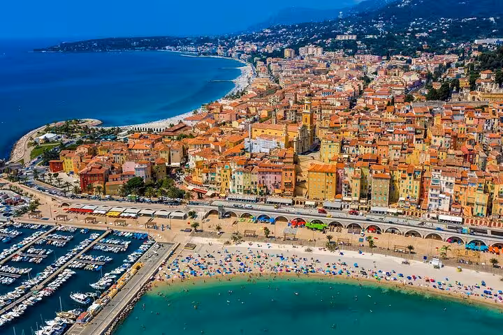 Aerial view of colorful Menton coastline on the French Riviera, featuring vibrant beaches and lively marina.