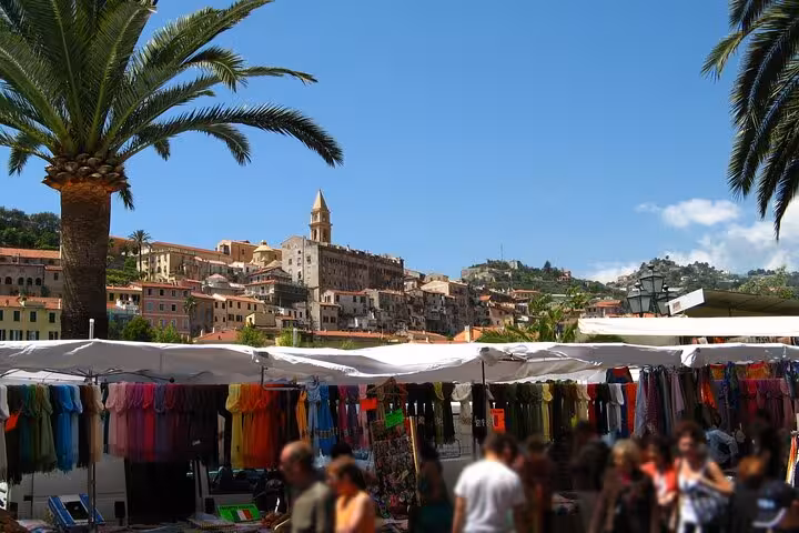 Vibrant market scene in Menton with colorful stalls and palm trees under a clear blue sky.