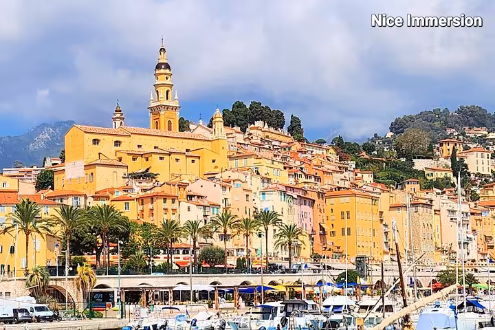 View of Menton's vibrant buildings and palm-lined waterfront on the Italy, France, Monaco day tour.