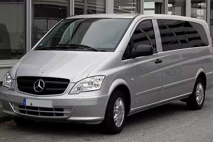 Modern silver Mercedes minivan used for private transfer service between Naples and Rome, parked outside terminal