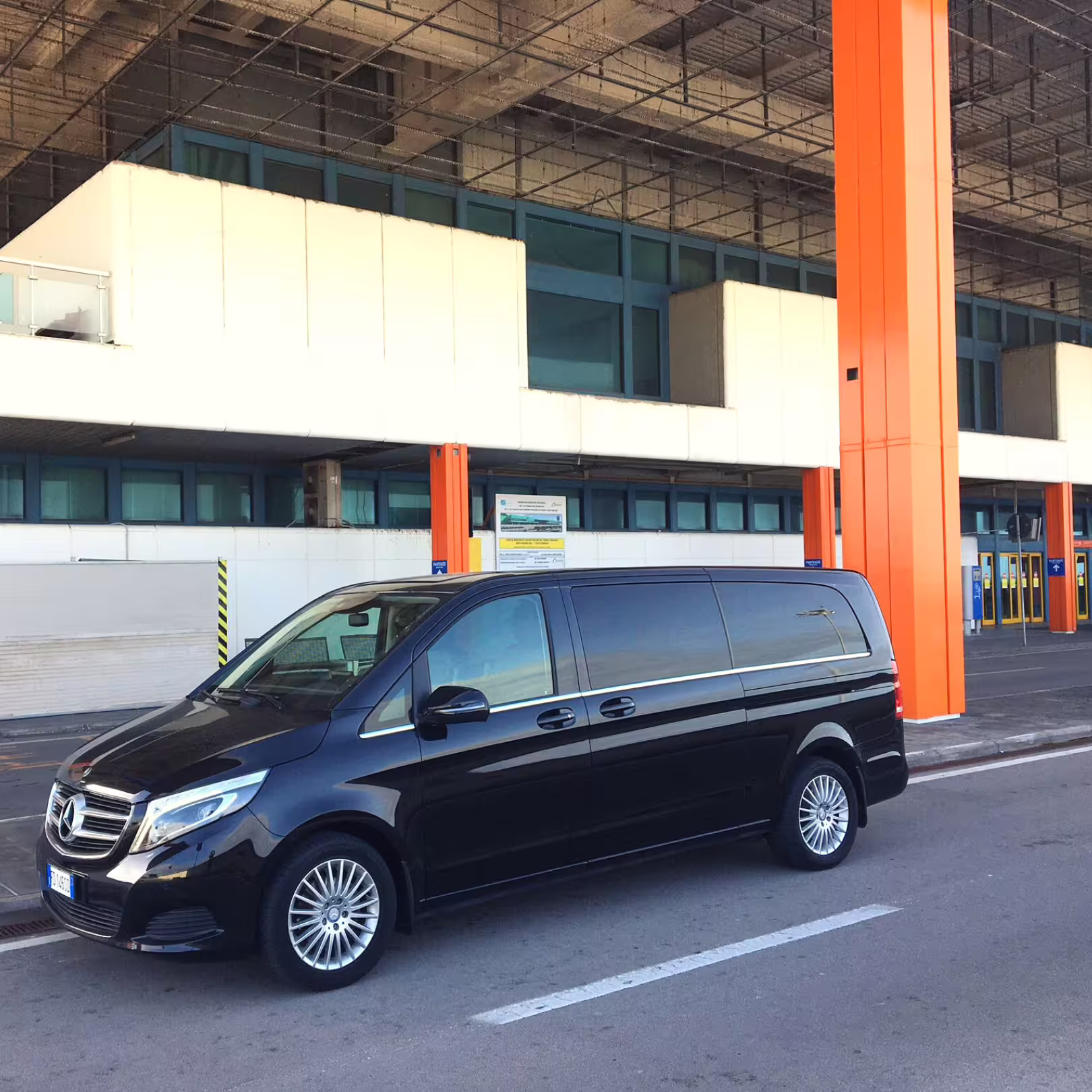 Black Mercedes minivan waiting outside Palermo airport terminal for a private transfer to NH Palermo Hotel in Sicily