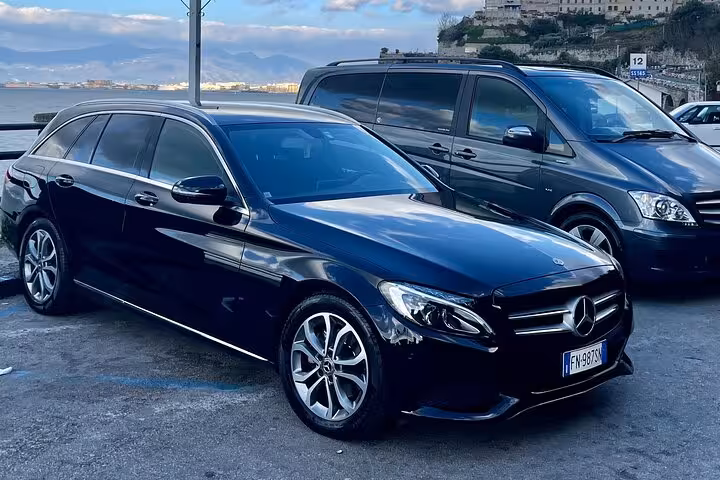 Elegant black Mercedes vehicles parked with scenic coastal views for Naples to Sorrento or Positano transfer.