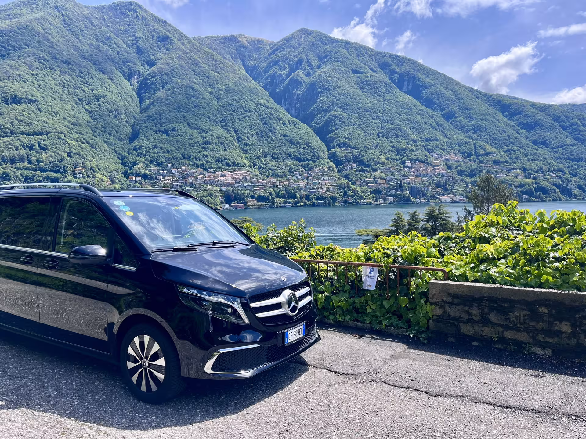Mercedes van with stunning mountain and lake backdrop, showcasing Milan to Florence scenic travel route.