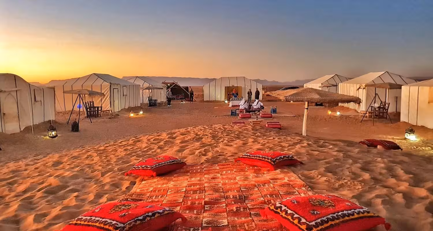 A vibrant desert camp setup with colorful cushions at sunset, part of the Merzouga 3-Day Desert Safari experience.
