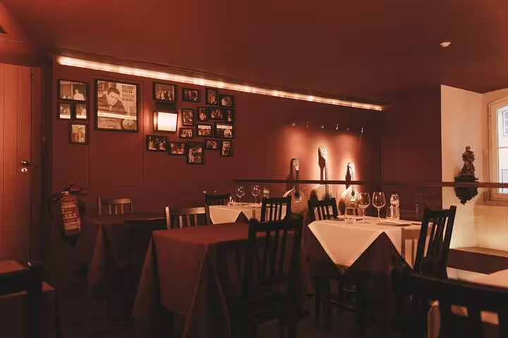 Intimate dining setup at Mesa de Frades, featuring elegant table settings and cultural wall art in Lisbon.