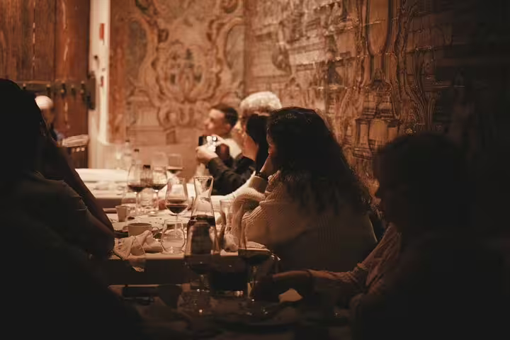 Diners immersed in a warm ambiance at Mesa de Frades, Lisbon, with intricate wall designs enhancing the Fado experience.