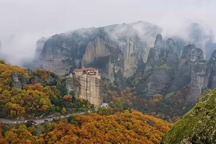 Misty Meteora monasteries above autumn forest and dramatic cliffs, highlight of a full-day private tour from Kalambaka
