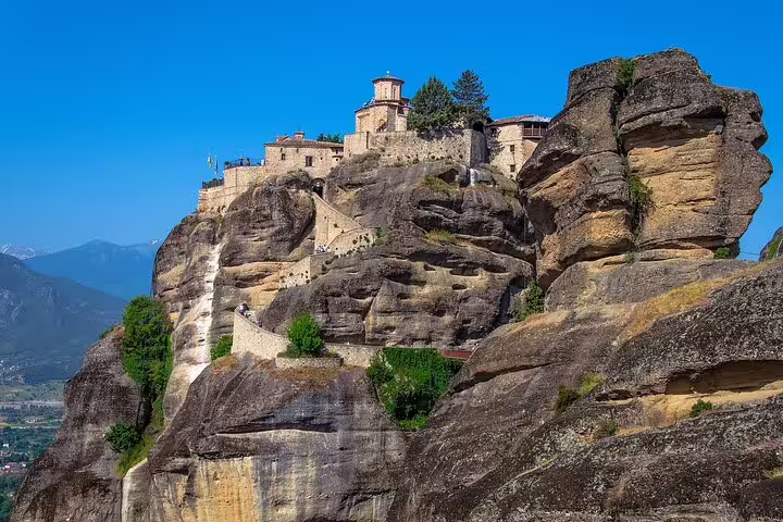 Close-up of a Meteora monastery perched on massive rock formations against a clear blue sky, ideal for cultural exploration.