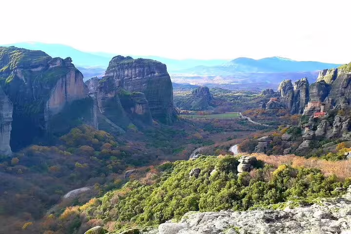 Scenic view of Meteora's towering rock formations and lush valley on a classical tour from Athens.