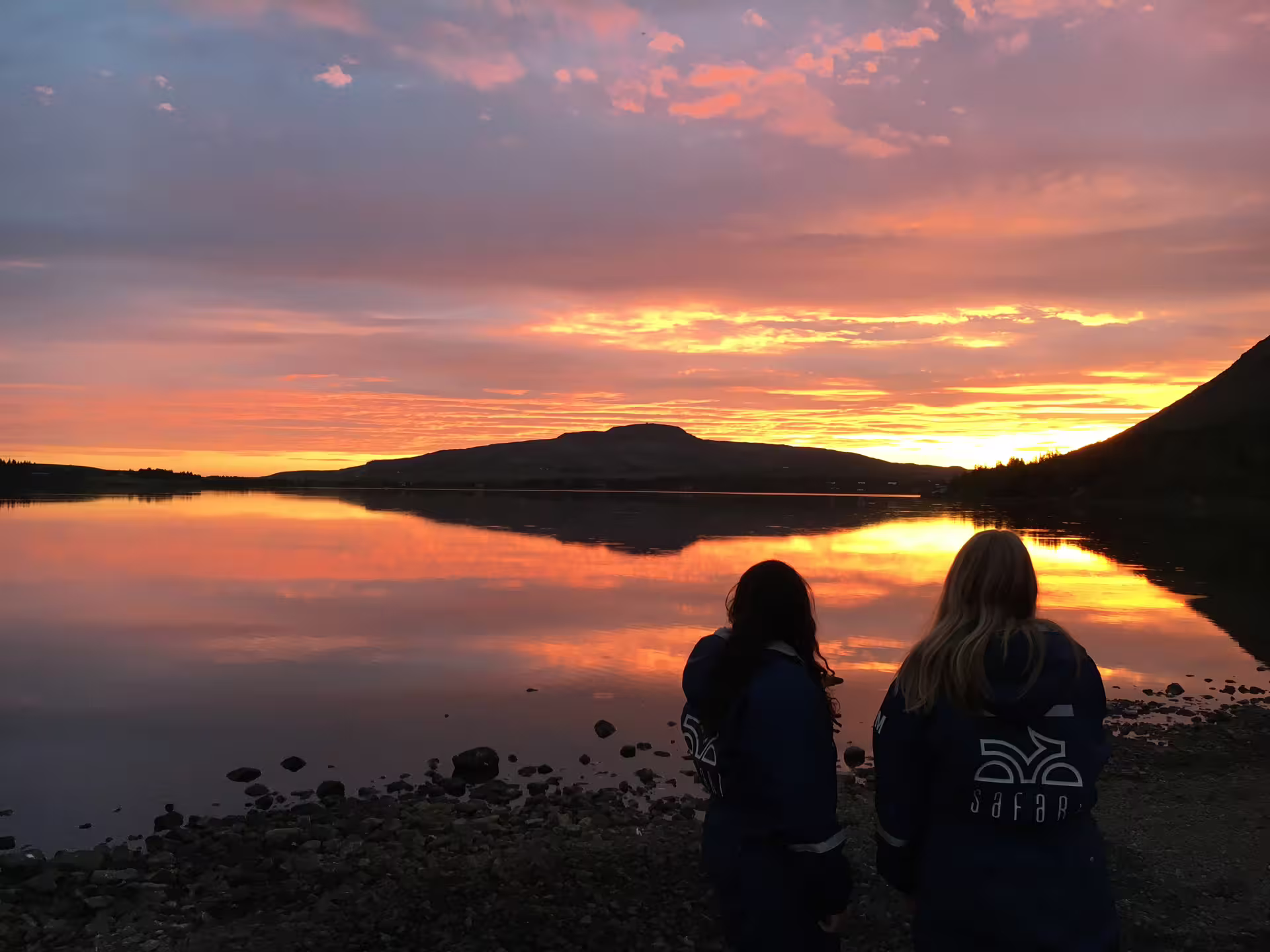 Participants enjoy the breathtaking view of the midnight sun over a tranquil lake during a 2-hour ATV tour adventure.