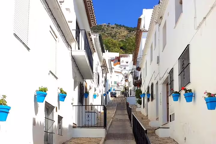 Whitewashed street in Mijas Pueblo with blue flower pots on Costa del Sol day trip to Marbella and Puerto Banus