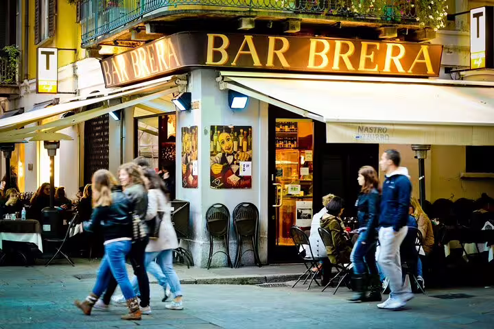 Visitors stroll past the vibrant Bar Brera, a lively spot on a bustling street, captured during a Milan Must-Sees private tour.