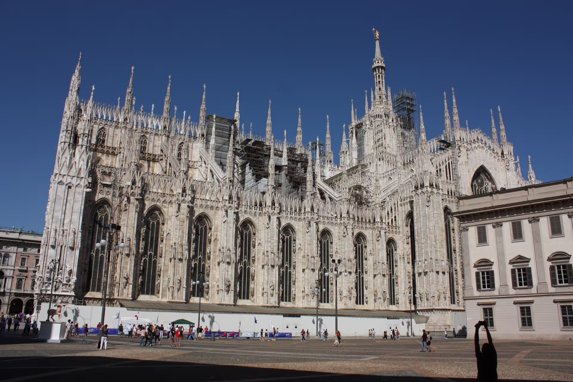 Sunlit view of Milan Cathedral’s ornate Gothic façade against a blue sky, a highlight stop on an Italian fashion and culture tour.