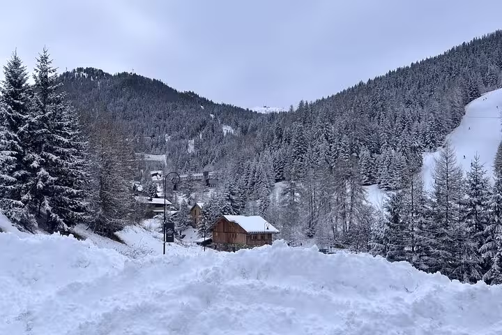Scenic winter view of snow-covered Courchevel, surrounded by pine forests and mountain peaks.