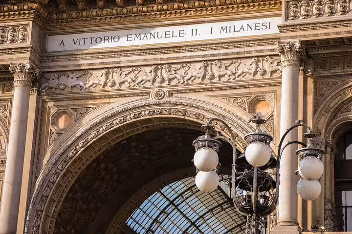 Intricate stonework and grand archway of Galleria Vittorio Emanuele II in Milan, showcasing stunning architecture on walking tour.