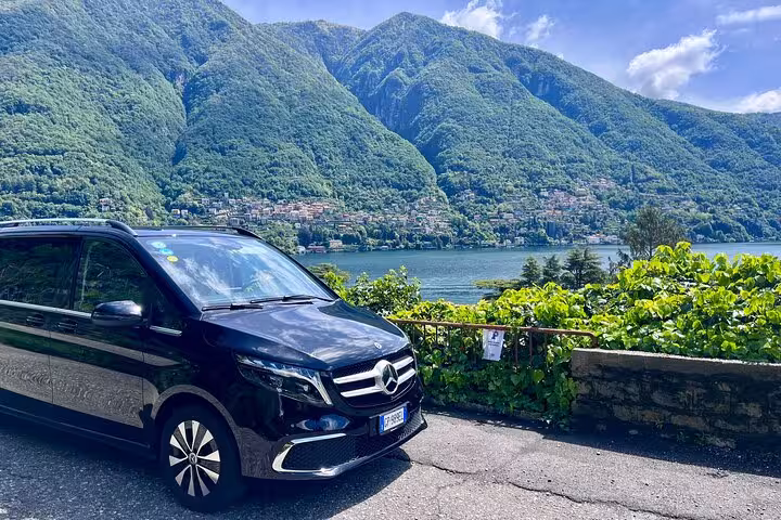 Elegant black van with stunning lake and mountain backdrop, perfect for Milan MXP to Milan seamless transfers.