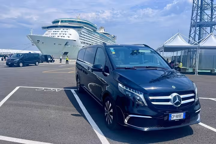 Premium black van ready at port with cruise ship, offering convenient Milan MXP airport to Milan transfers.