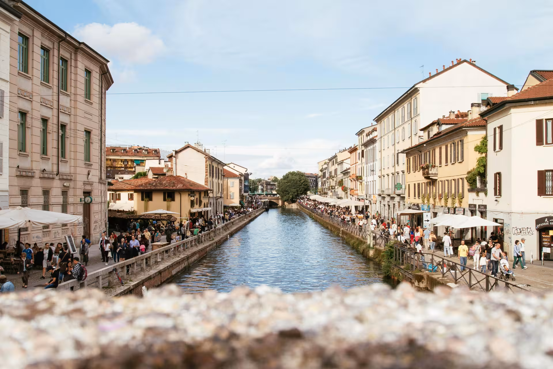 Scenic view of Navigli district in Milan with bustling canalside cafes and historic architecture.