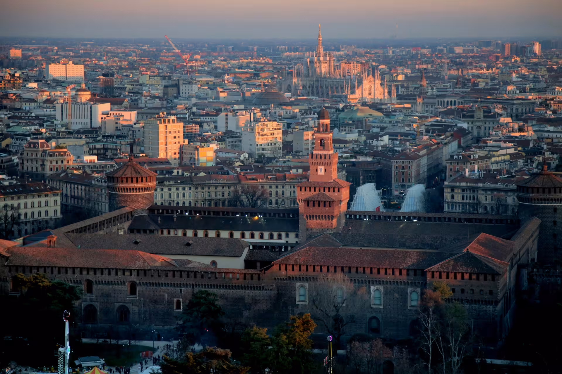 Aerial view of Milan's historic Sforza Castle with cityscape and sunset, perfect for Milan MXP airport transfers.
