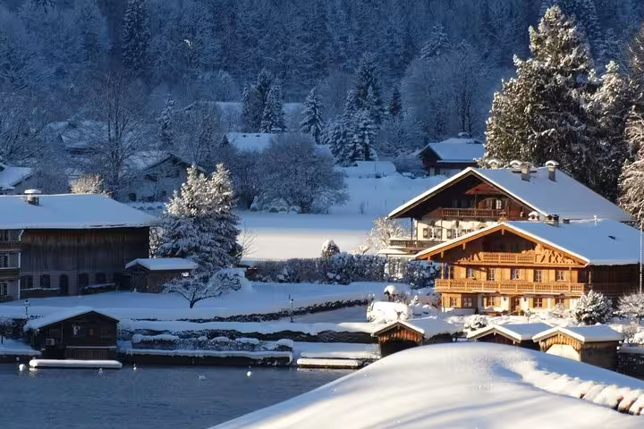 Charming snow-covered chalets by a serene lake en route from Milan to St. Moritz, highlighting winter tranquility.