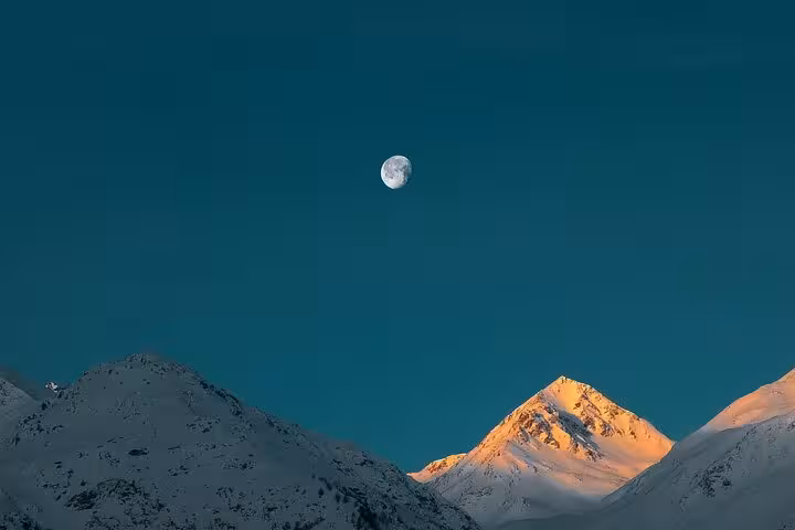 Scenic moonlit view over snow-capped mountains in the Swiss Alps during a clear night.