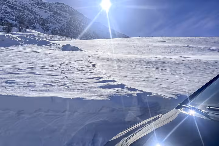 Sunny alpine landscape with a sleek black car on the Milan to Zermatt Tasch private transfer route.