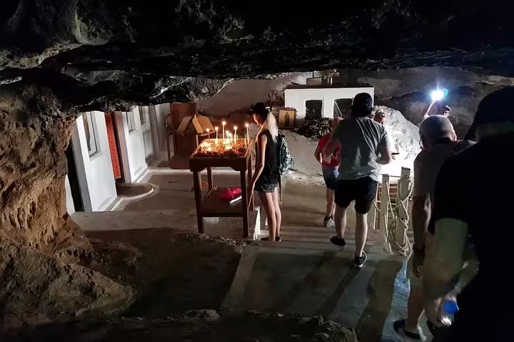 Visitors exploring the candle-lit Milatos Cave, a historical site included in the Island Spinalonga tour.