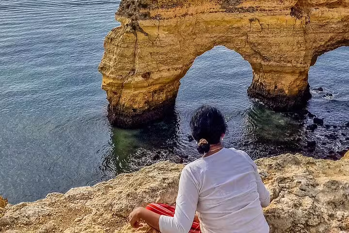 Tourist admiring the stunning coastal rock formations on the Milfontes to Algarve private tour with Benagil caves boat trip.