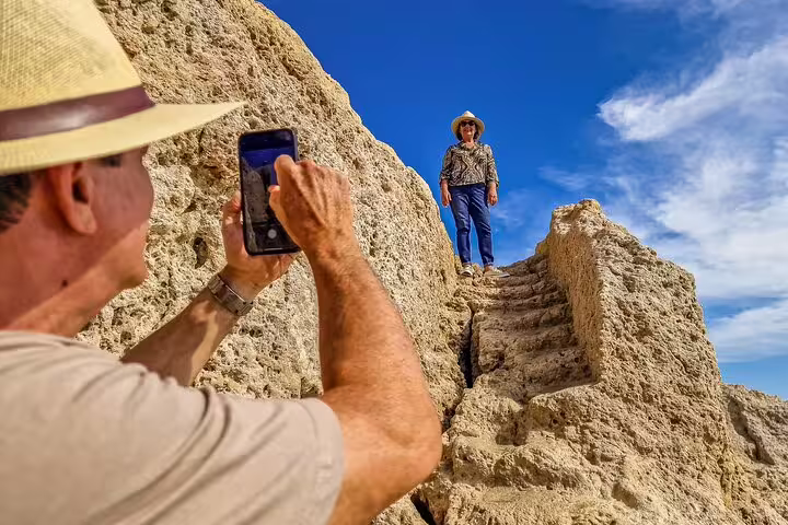 Tourists enjoy capturing memories on rocky cliffs during the Milfontes to Algarve private tour with Benagil caves boat trip.