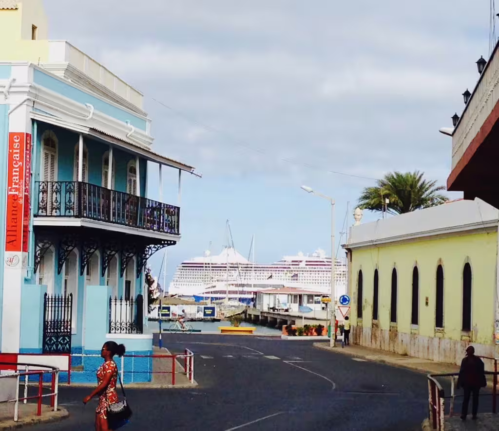 Colorful colonial architecture in Mindelo with a view of the harbor and a cruise ship, perfect for a city walking tour experience.